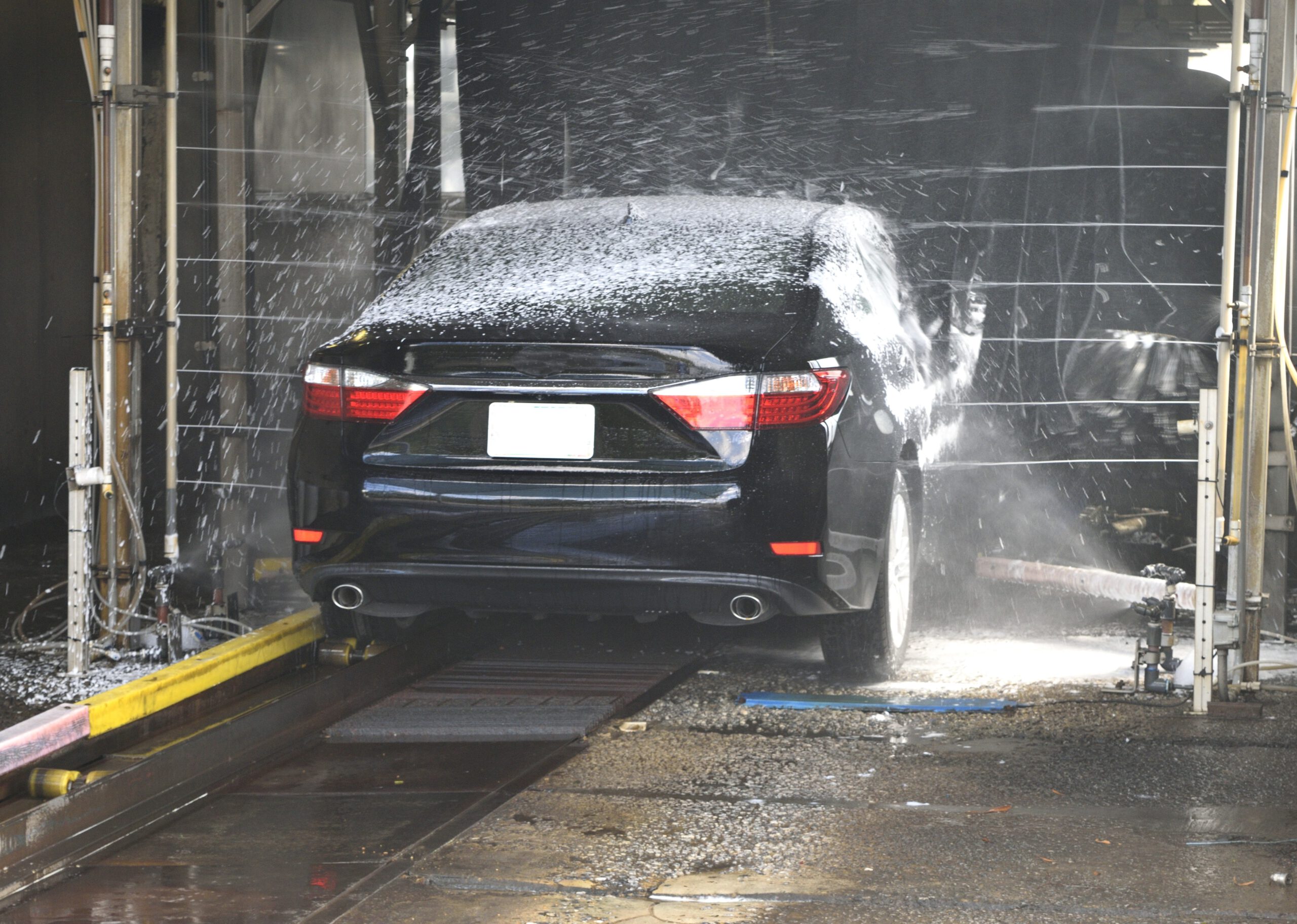Czarny samochód na automatycznej myjni samochodowej podczas mycia